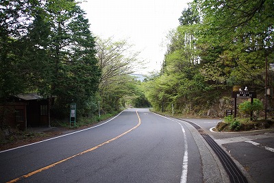 まっすぐ続く大きな道路と、右に入る道に立つ看板の写真