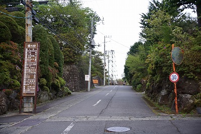 まっすぐ続く道の左側に案内看板が見える写真