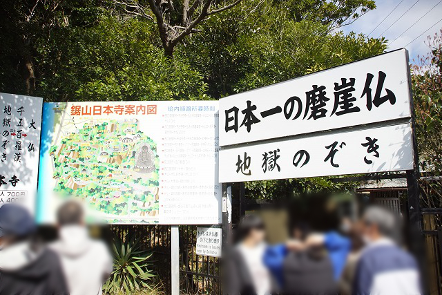 日本一の磨崖仏、地獄のぞきと書かれた入り口と、その横に立つ鋸山日本寺案内図の写真