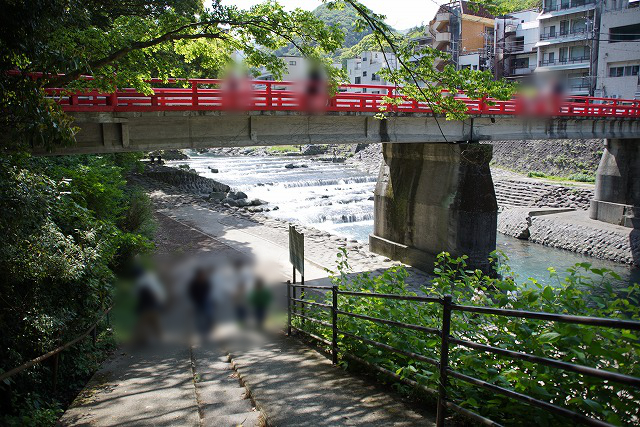 河原に降りる坂道と、向こうに見える真っ赤な橋の写真