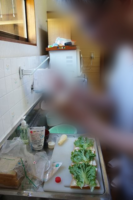 Foto de gente poniendo verduras sobre pan en una tabla de cortar