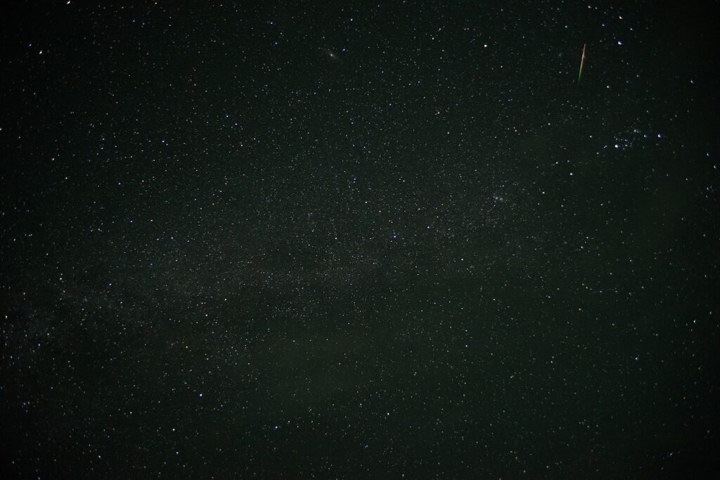 右上に流星が短い線となって写った写真