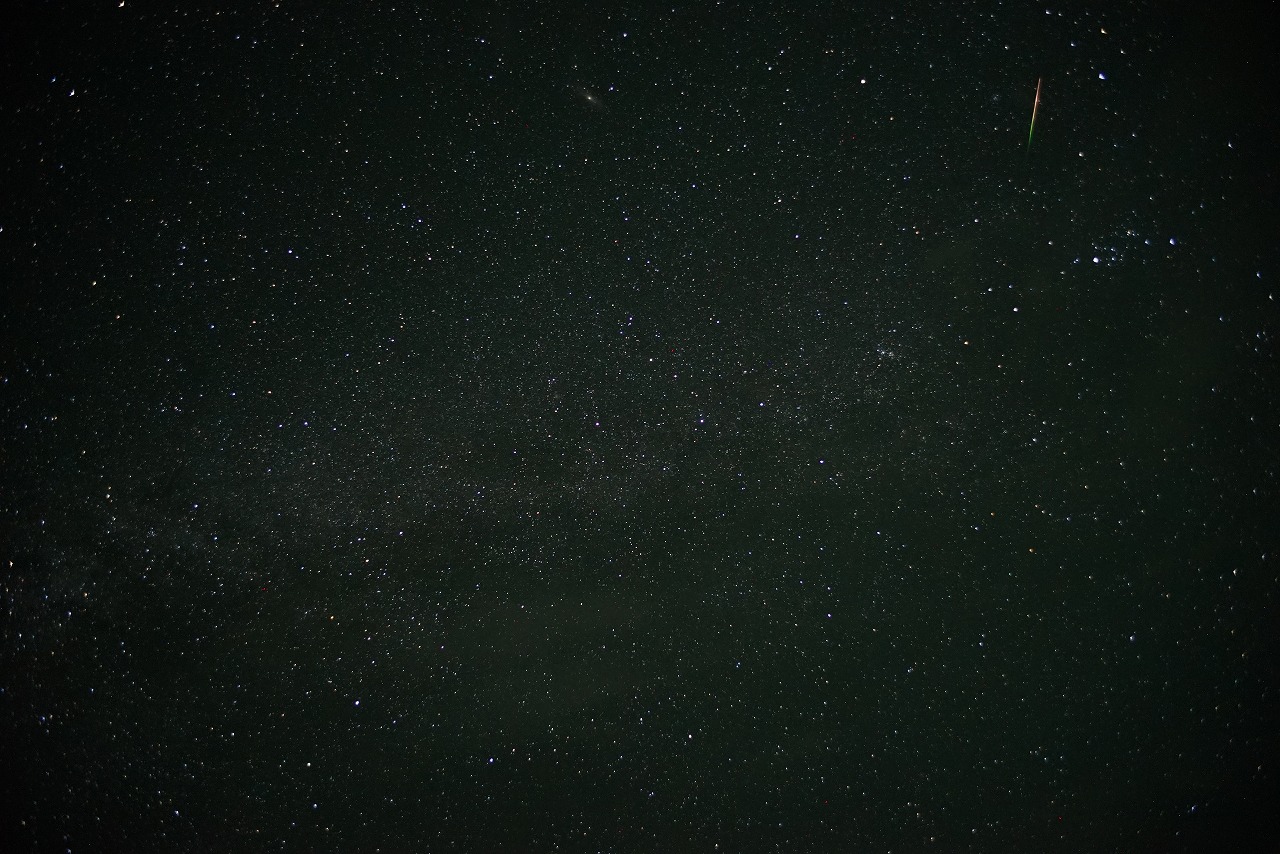 右上に流星が短い線となって写った写真