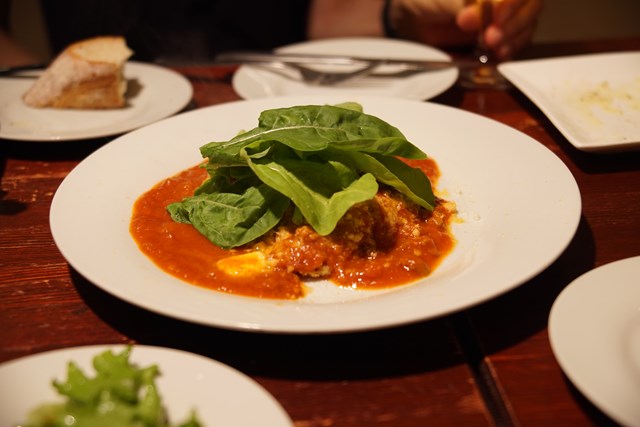 Foto de una chuleta con la salsa de carne justa para absorberla y verduras de hoja verde como las espinacas