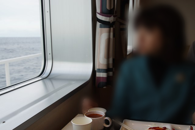 Foto de una persona sentada junto a la ventana. El mar se puede ver fuera de la ventana