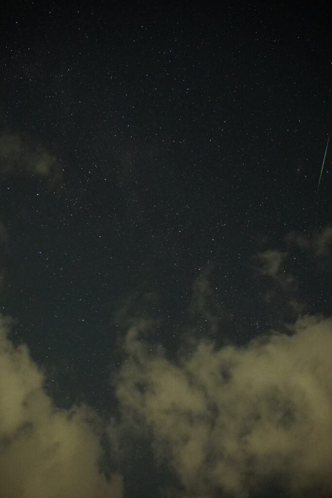 写野の右端やや上に流星が左下から右上への線として写っている星空の写真