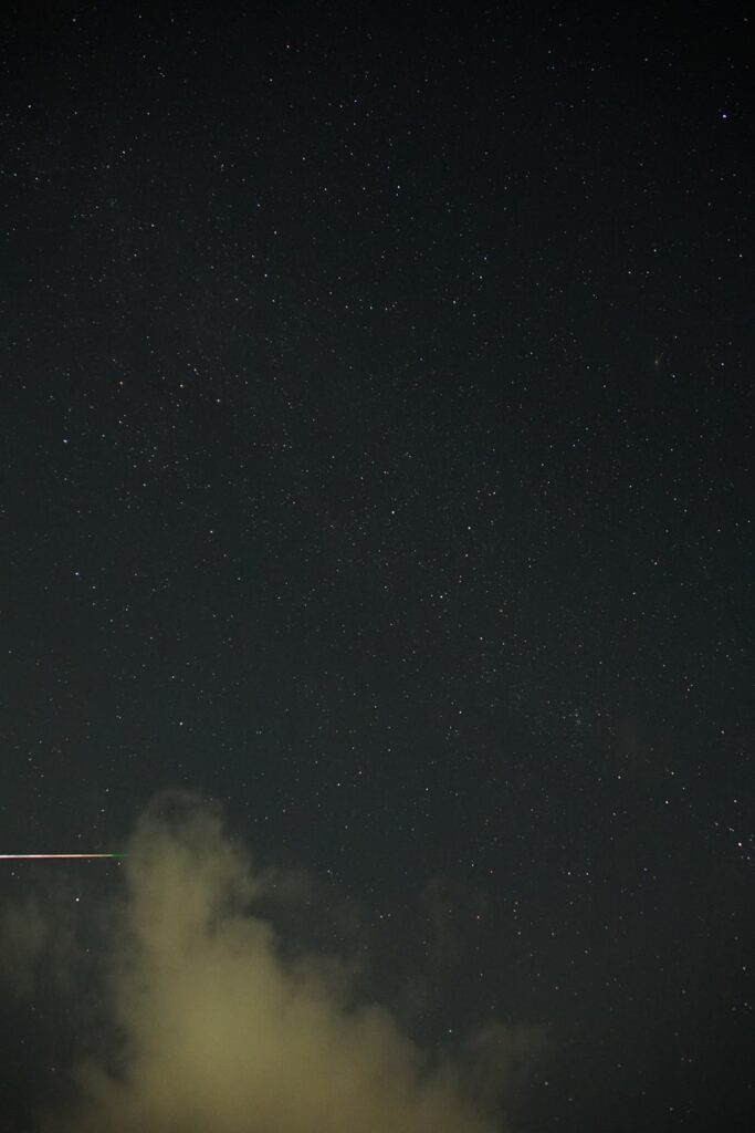 写野の右端下に流星が右から左への線として写っている星空の写真