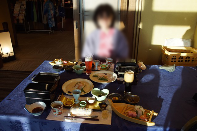 テーブルの上の料理を前に椅子に座る人の写真
