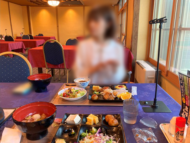テーブルの上の料理とその向こうに座る人の写真